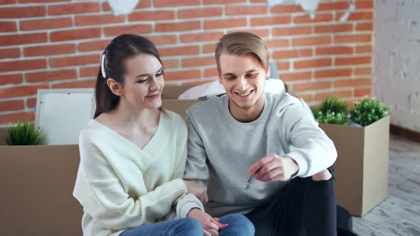 Young Smiling Couple Enjoying Purchase and Moving to New Apartment Holding Keys By Hand Medium Shot