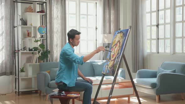 Asian Artist Man Coming To Sit nd Holding Paintbrush Painting A Girl's Hair On The Canvas