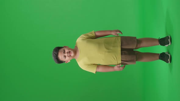 Full Body Of Asian Little Boy Warmly Smiling On Green Screen Background In The Studio