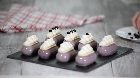 Confectioner decorates mousse cake with a blueberries Production of glazed desserts