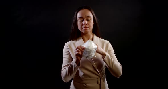 Portrait of a Woman with Long Hair and a Formal Dress on a Black Background. She Holds a Disposable