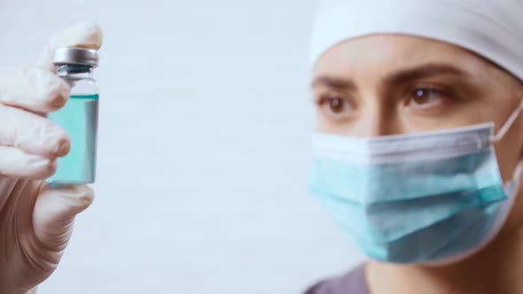 Doctor in White Gloves Holding Glass Vial with Medicine