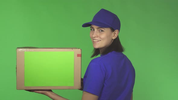 Rear View Shot of a Delivery Woman with a Cardboard Box Smiling Over Her Shoulder