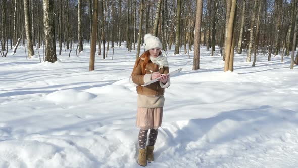 Redhead Girl Staying At Winter Park And Draws In Sketchbook. Beautiful Teen Girl Paints On Paper