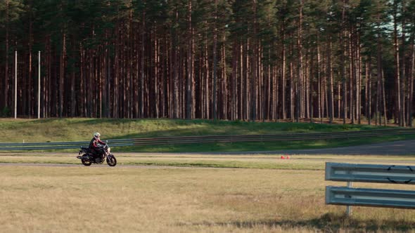 Motorcyclist on motorbike is practicing for race on asphalt road in forest.