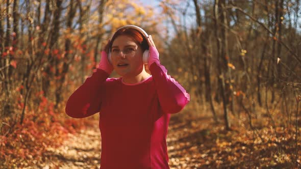 Active Young Girl in Sportswear Puts on Wireless Headphones to Start Jogging Workout Along Outdoor