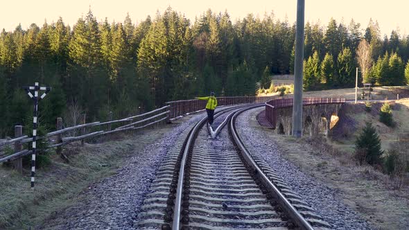 A Woman with a Backpack Walks on the Railway