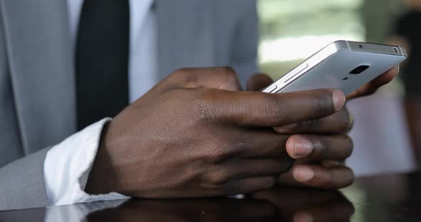 Black Male Hands Using Smart Phone Touchscreen in Cafe