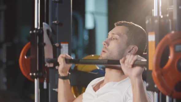 Muscular Man Doing Workout Exercise With Barbell Machine Training Hands Back and Shoulders in Gym