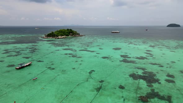 Aerial Rising Shot Over Moored Traditional Longtail Fishing Boats In Waters In Koh Lipe With Reveal
