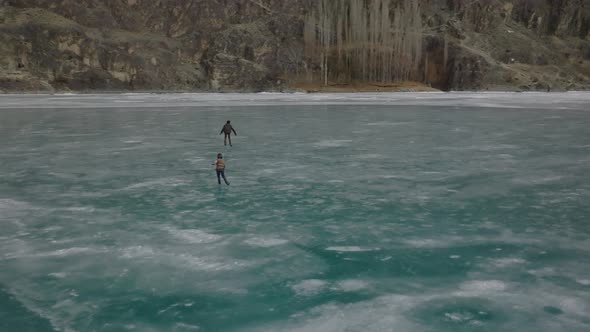 Many people go outside on the frozen lake to ice skate. A 4k cinematic drone shot made in khalti lak