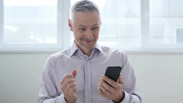 Middle Aged Man Excited for Success While Using Smartphone