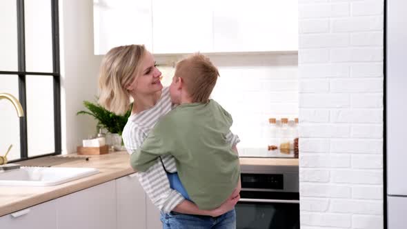 Excited Mom or Babysiter and Kid Boy Jumping Dancing Laughing in Modern Scandinavian House Kitchen