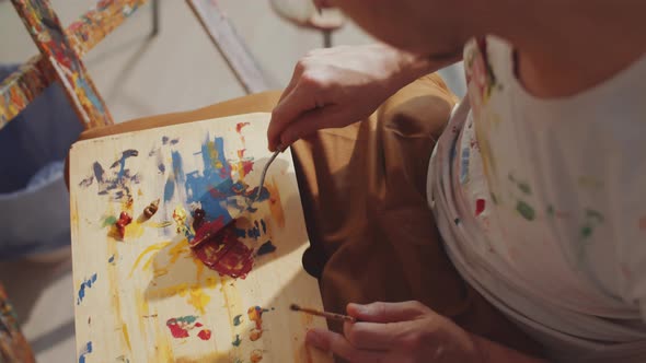 Artist Mixing Paint Colors on Wooden Palette