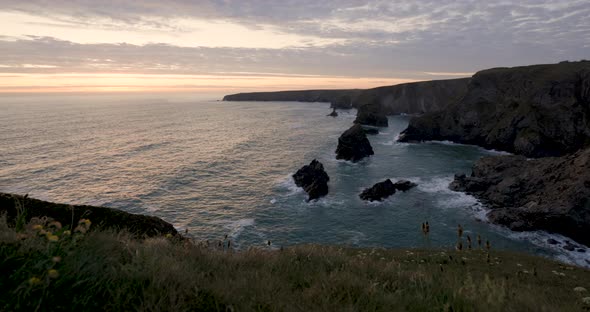 Aerial panoramic slow motion view of ocean waves against rock stacks in Cornw