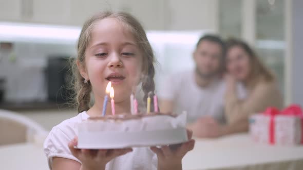 Cute Happy Caucasian Girl Making Wish and Blowing Candles on Birthday Cake Looking Back at Joyful