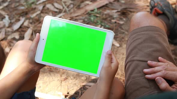 Father and son using digital tablet outside tent