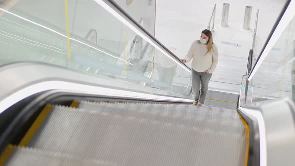 a Young Woman in a Protective Mask Climbs an Empty Escalator