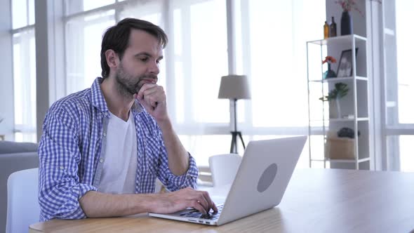 Pensive Casual Beard Man Thinking and Working on Laptop