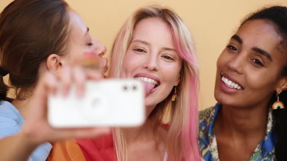 A close-up view of a group of multi-ethic women are taking selfie photo using phone enjoying pride g