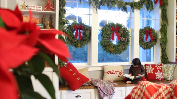 Young girl reading book in house decorated for Christmas