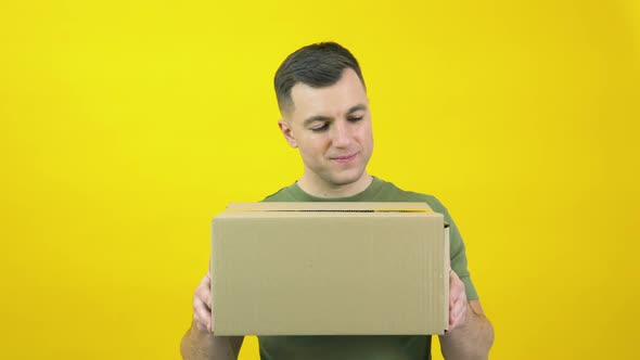 Caucasian Middleaged Man in a Green Tshirt Lifts a Craft Cardboard Box in Front of Him