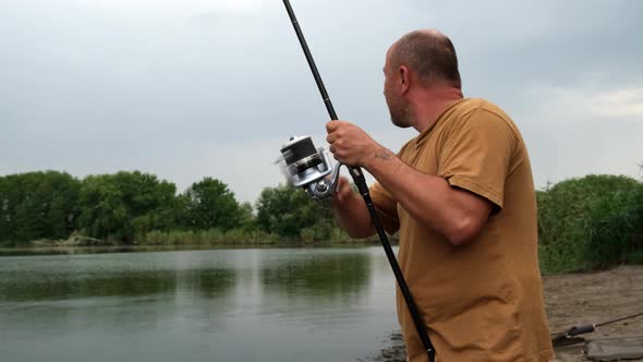 Fisherman Pulls the Fish Out of the River with Carp Fishing Equipment