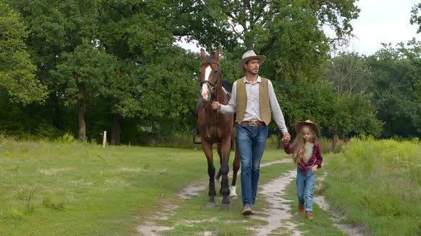 Cowboy with His Daughter Walking with a Horse on a Forest Road