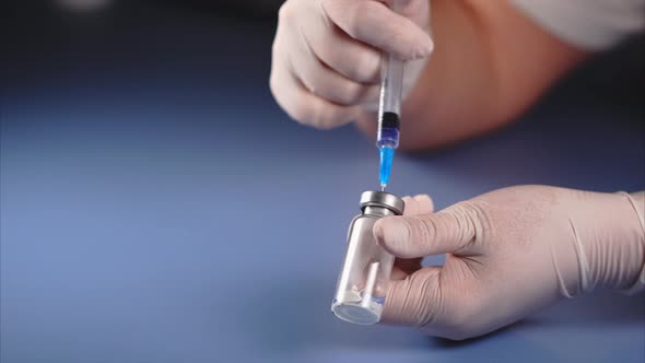 Mixing of Medicine. Doctor Piercing the Lid of the Ampoule with Syringe