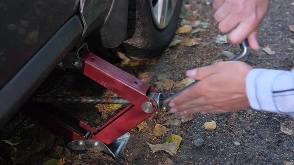 Close Up Woman Trying Jack To Lift a Car in the Forest. Travelling Trouble.