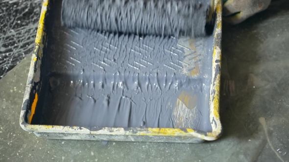 Builder Sops Wet Roller In Yellow Pallet Filled With Gray Building Paint