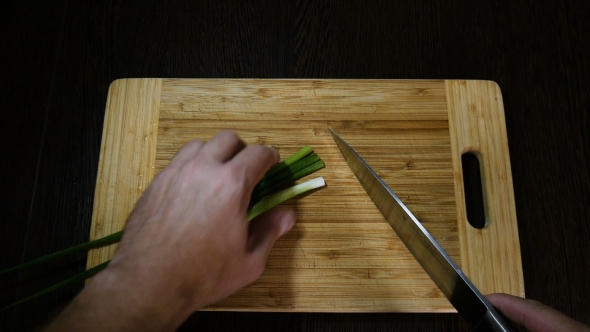 Chef Cutting Green Onions On Board