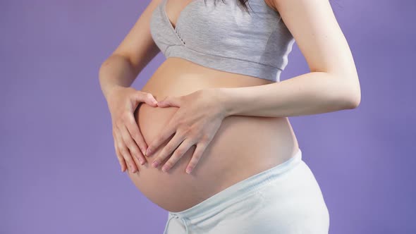 Loving Pregnant Woman Posing in Studio Over Purple