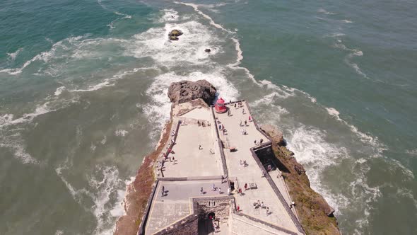 Aerial view tourists on Nazaré lighthouse descending reveal Atlantic Ocean horizon