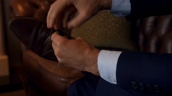 Low section of businessman tying shoelace on sofa 
