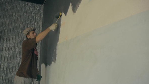 Man Is Actively Using a Fur Roller When Painting Walls Gray Paint.
