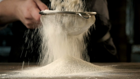 Chief's Hands Sifting Flour Through a Sieve For Baking