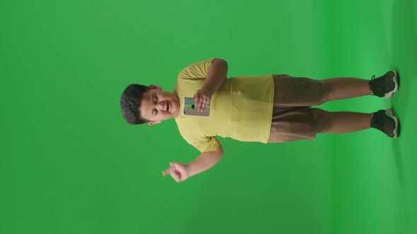 Full Body Of  Asian Little Boy Flipping Through The Phone With Pointing To The Side On Green Screen