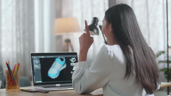 Asian Female Footwear Designer Thinking Then Raising Index Finger While Designing Shoe On A Laptop