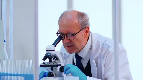 Senior Lab Technician Examining Samples and Liquid Using Microscope