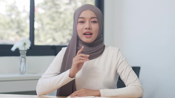Asia muslim lady looking at camera talk to colleagues about plan in video call in new normal office.