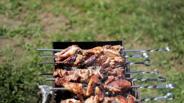 Chicken And Pork Grilled On Charcoal In a Barbecue. Meat Rotates And Has Golden Skin. Moving The