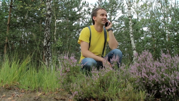 Man Hiker Walking Through The Forest And Talking On The Phone. Yellow T-shirt And Jeans With