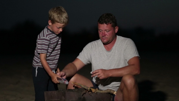 Father With Son Kindling a Fire In The Grill