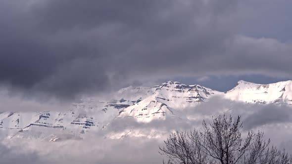 Snow covered mountain surrounded by clouds moving in