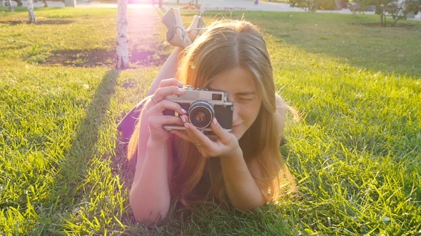 Woman The Photographer With Old Camera Lays On a Grass