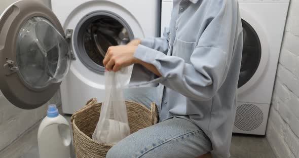 Woman Puts Clothes Into a Laundry Bag