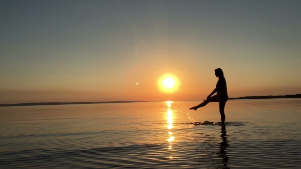 A Young Girl Splashes Water At Sunset