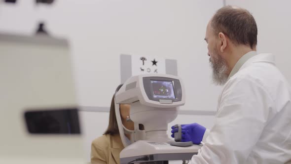 Optometrist Checking Eyes of Female Patient with Autorefractor