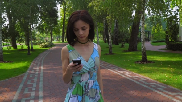 A Young Girl Goes On a Path In The Park And Gaining a Message On The Phone.